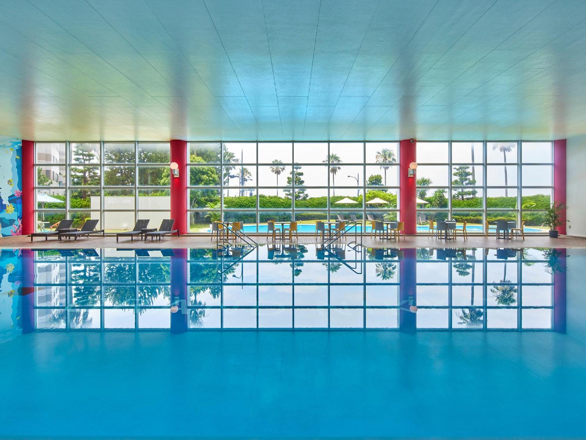 Hotel Grand Nikko Tokyo Bay Maihama Urayasu Exterior foto The photo shows an indoor swimming pool with bright blue water. The pool area is spacious, characterized by large windows that allow natural light to flood in, creating a vibrant atmosphere. The walls are painted in a soft color, with accents of red.